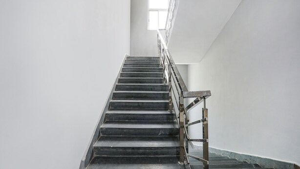A staircase with a metal handrail and a window at the top. - Fabhotel Sonnet Inns (Ranchi)