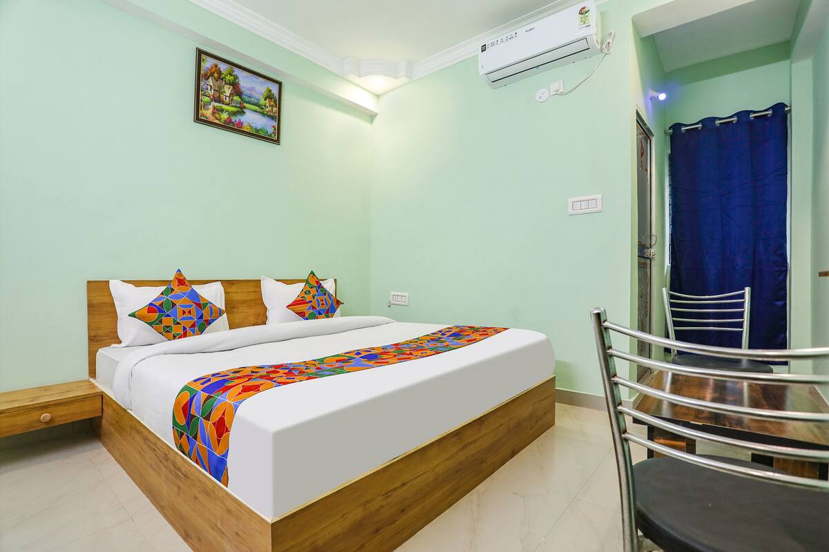 Una cama bien hecha con un edredón colorido, un cabecero de madera y un cuadro en la pared.