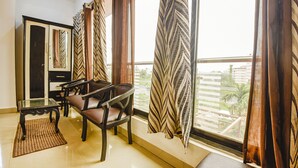 Una habitación con sofá, una mesa de cristal y cortinas.