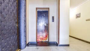 A hallway with a marble floor leading to a door with a glass panel. - Fabhotel Four Boutique (Jaipur)
