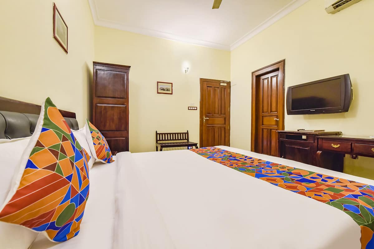 A hotel room with a bed, a television, a desk, and a chair.