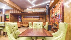 A restaurant with a wooden interior, green upholstered chairs, and a long wooden table. - Fabhotel Four Boutique (Jaipur)