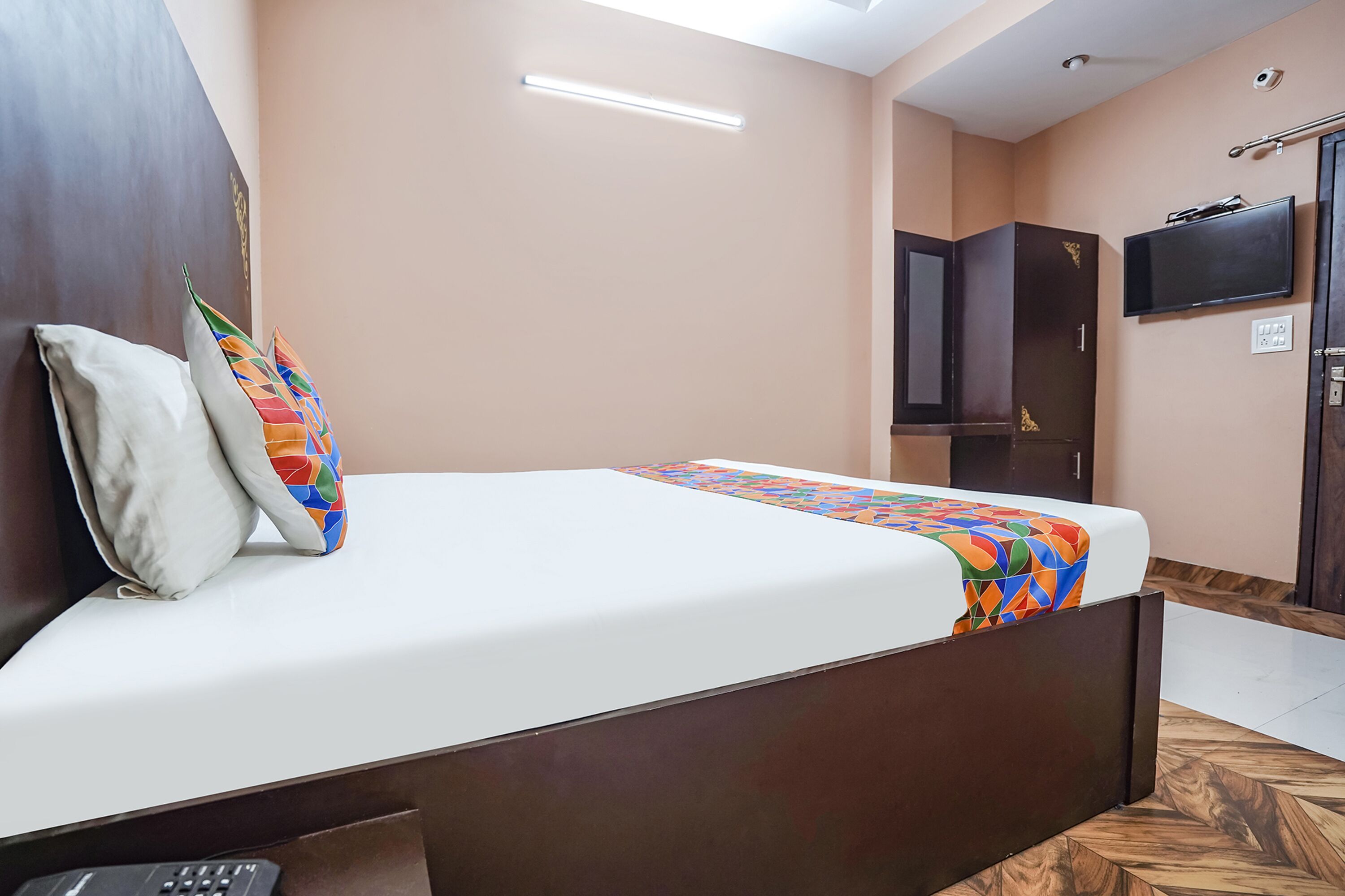 A hotel room with a bed, a TV, a wardrobe, and a desk with a keyboard.