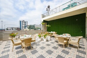 An outdoor patio area with wicker furniture and potted plants. - Fabhotel Bleu Ville (Faridabad)