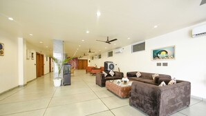 A spacious lobby with a high ceiling, multiple ceiling fans, and a large seating area with sofas and a coffee table.