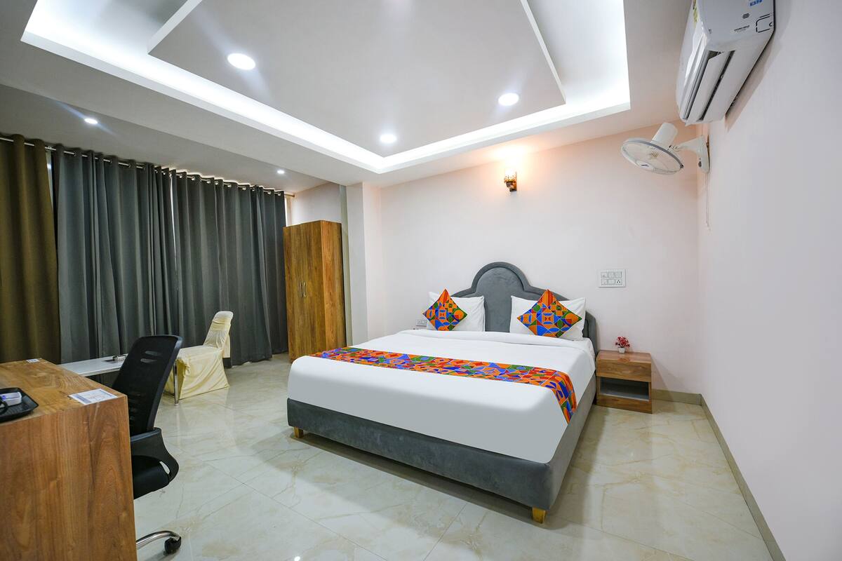Habitación de hotel con cama, escritorio, silla y lámpara en el techo.