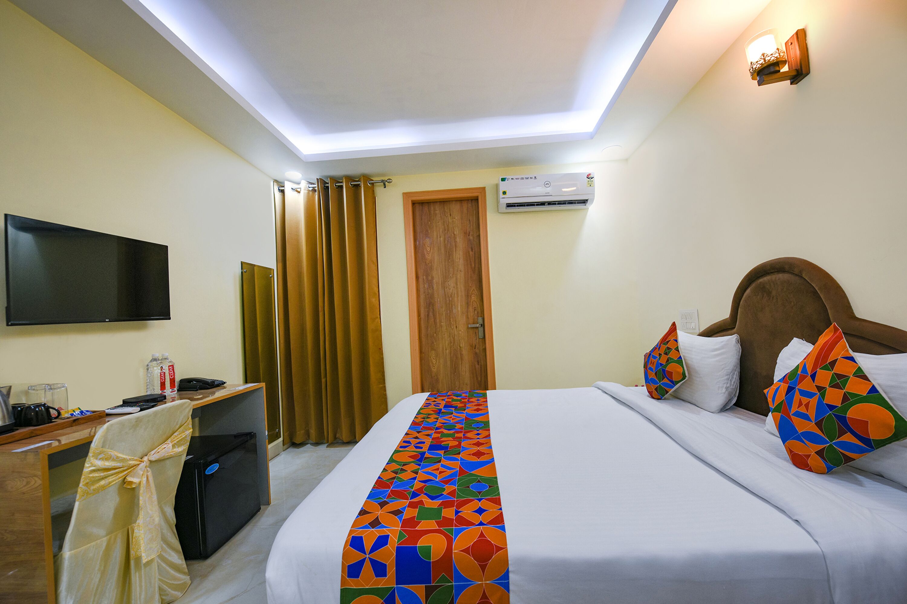 Una habitación de hotel con cama, escritorio, televisor y aire acondicionado.