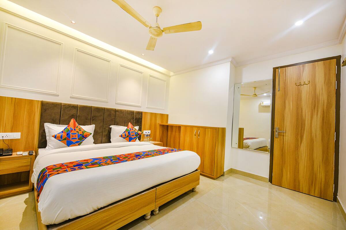 A bedroom with a bed, wooden headboard, ceiling fan, and a wardrobe.