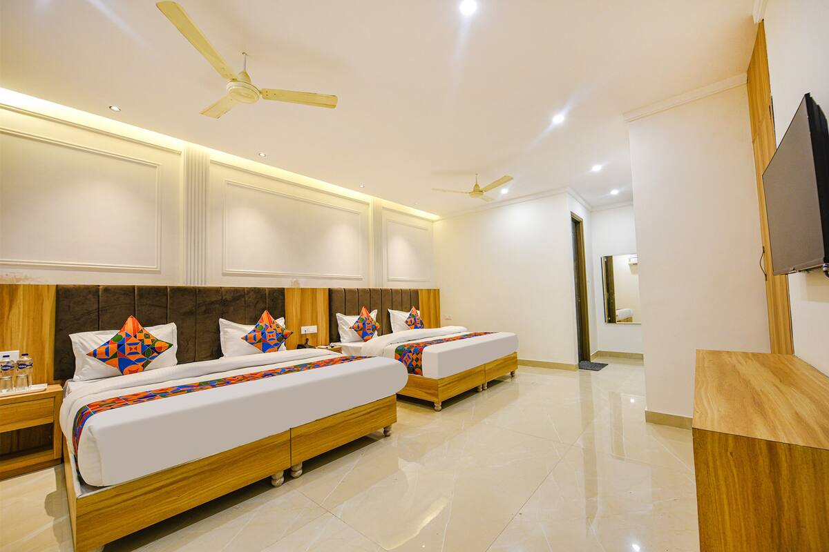 A hotel room with two beds, a TV, and ceiling fans.