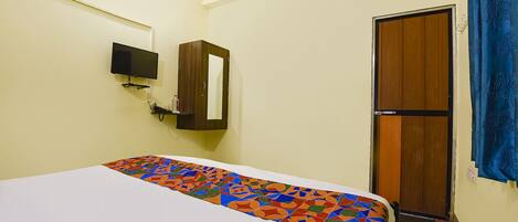 Una habitación con una cama, un televisor en la pared, un armario y una puerta.