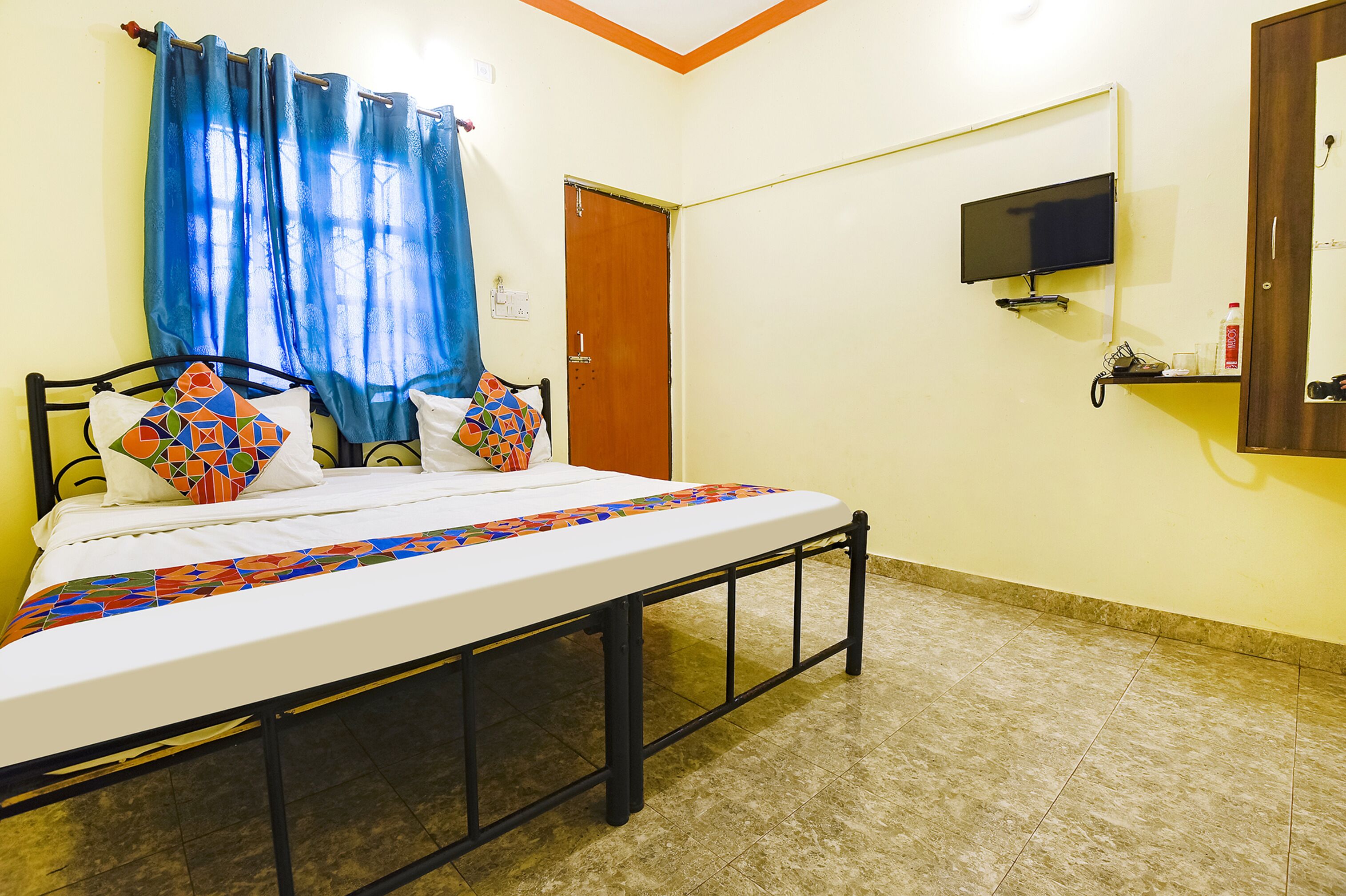 A bedroom with a bed, curtains, a television, and a door.