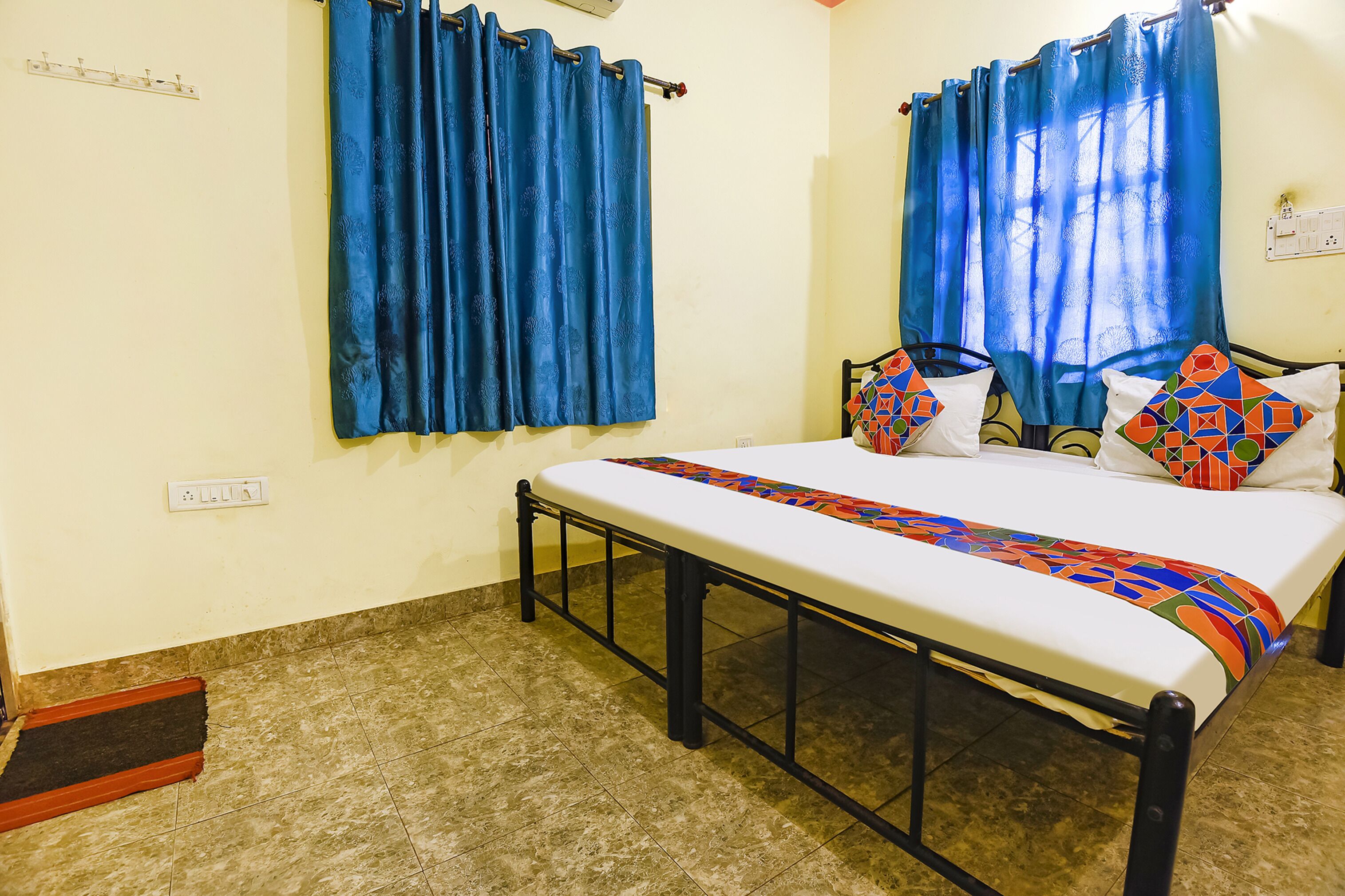 A bed with a patterned bedspread, a black metal frame, and two pillows with geometric designs.