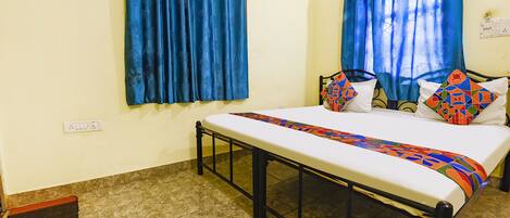 A bed with a patterned bedspread, a black metal frame, and two pillows with geometric designs.