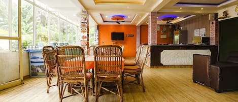 A restaurant with a wooden floor, wicker chairs, and a reception desk.