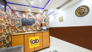 Un mostrador de recepción con un cartel de 'Fab Hotels' y una pared decorativa con un diseño geométrico.