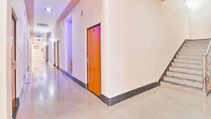 Un corridoio d'albergo con pavimento lucido, una porta in legno e una scala.