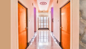 Un corridoio con porte in legno, pavimento piastrellato e soffitto decorato con un motivo circolare.