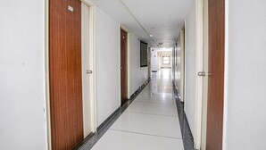 Un lungo e stretto corridoio d'hotel con porte in legno e pareti bianche.