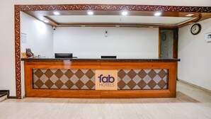 Una reception con una insegna 'fab hotels', un orologio e una telecamera di sicurezza al muro.