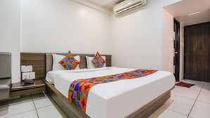 Una camera d'albergo con un letto grande, un comodino con il telefono e un condizionatore d'aria a parete.