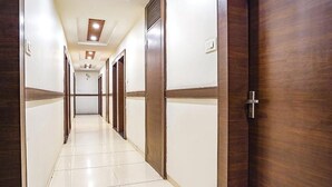 Un pasillo de hotel con puertas de madera, paredes blancas y suelo de baldosas.