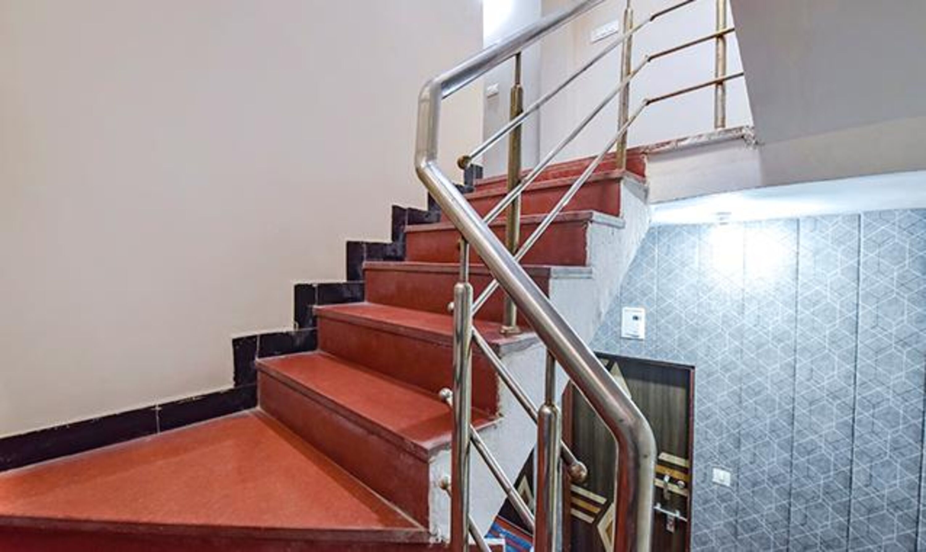 Una escalera con barandillas metálicas y escalones rojos.