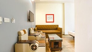 A living room with a brown sofa, beige armchairs, and a coffee table. - Fabhotel Sky Land (New Delhi)