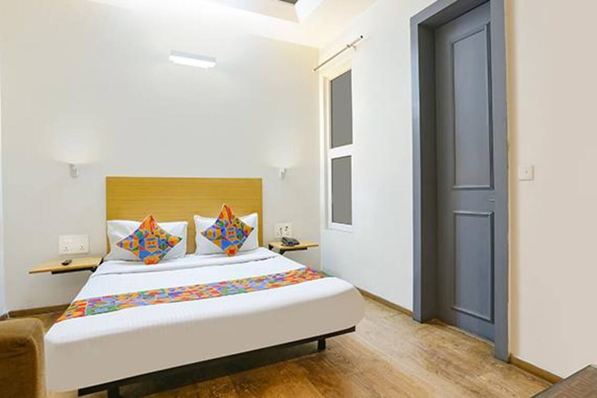 A bedroom with a bed, a wooden headboard, a bedside table, and a door.