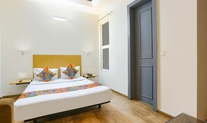 A bedroom with a bed, a wooden headboard, a bedside table, and a door.