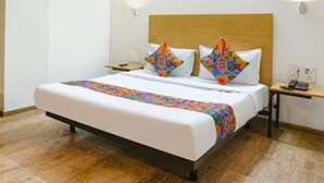 A hotel room with a large bed, a wooden headboard, two bedside tables, and a nightstand. - Fabhotel Sky Land (New Delhi)