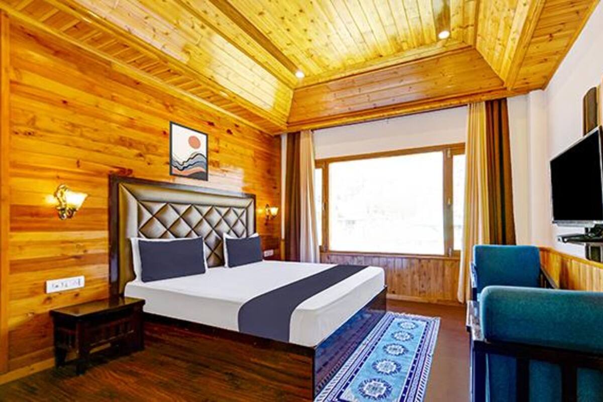 A wooden-paneled room with a bed, a TV, and a window.