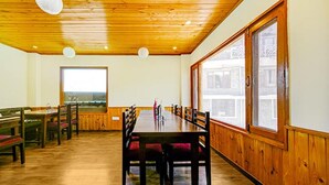A dining area with wooden walls and ceiling, a large window, and a view of a building outside.