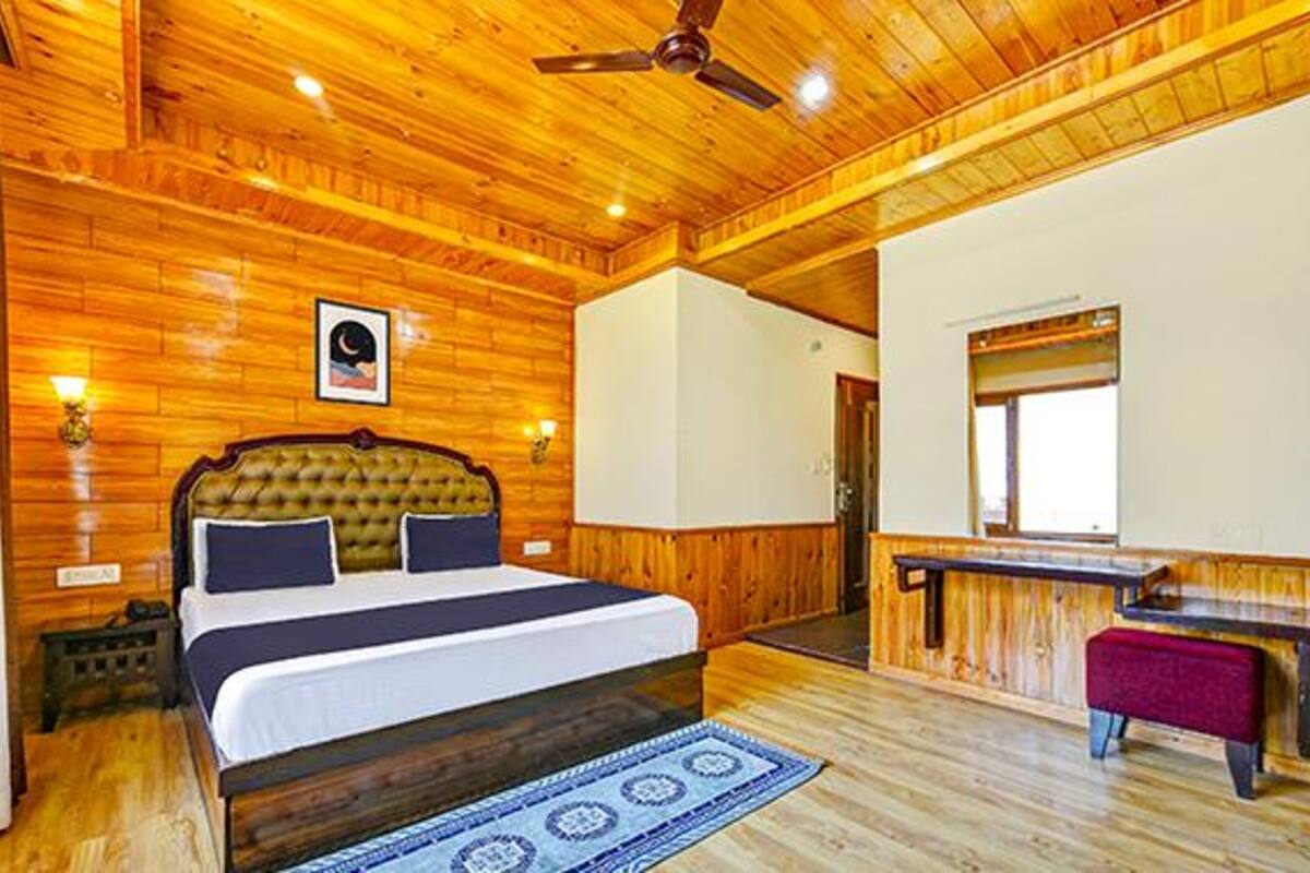 A wooden-paneled bedroom with a bed, bedside lamps, a ceiling fan, and a small bench.
