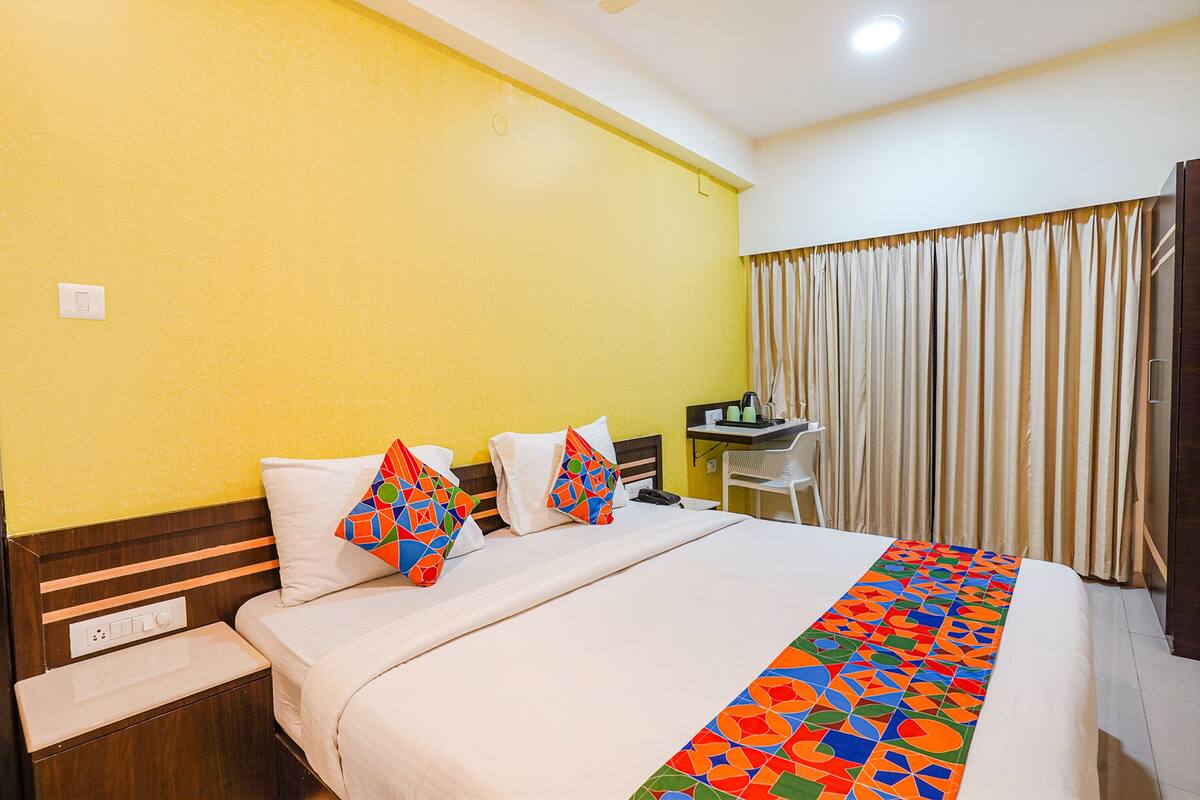A hotel room with a bed, a desk, and a chair.
