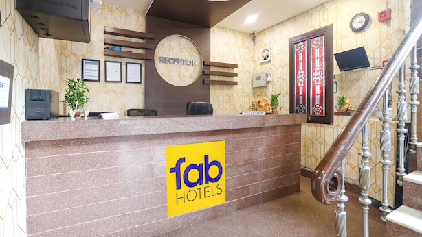 Zona de recepción de un hotel, con mostrador de recepción, un reloj y una escalera.
