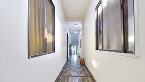 A narrow hallway with tiled flooring and large windows on both sides. - Fabexpress Nishesh Tower (Ujjain)