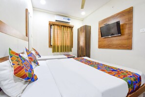 A hotel room with two beds, a TV mounted on the wall, an air conditioning unit, and a window with curtains. - Fabexpress Nishesh Tower (Ujjain)