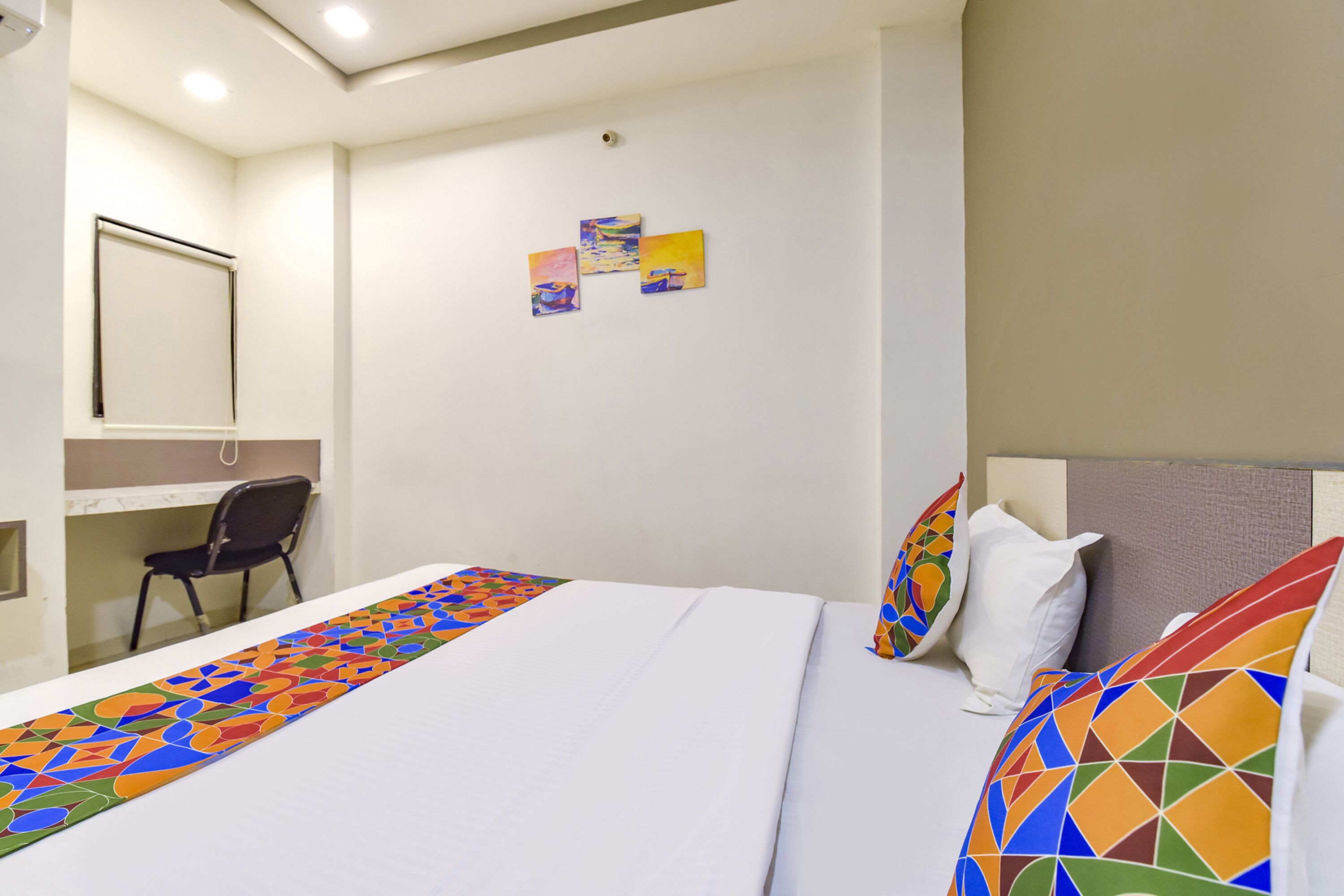 A hotel room with a bed, a desk, and a chair.