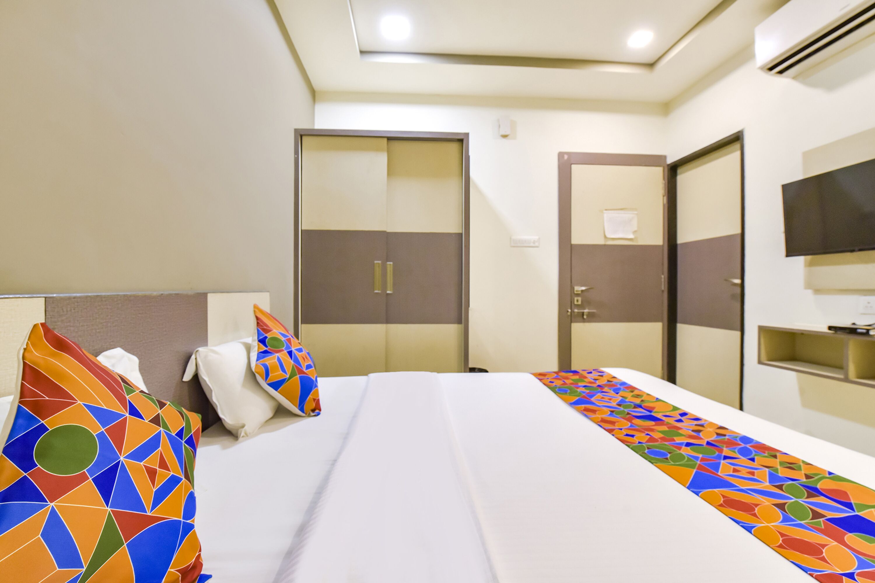 Una habitación de hotel con cama, armario, televisor y espejo.