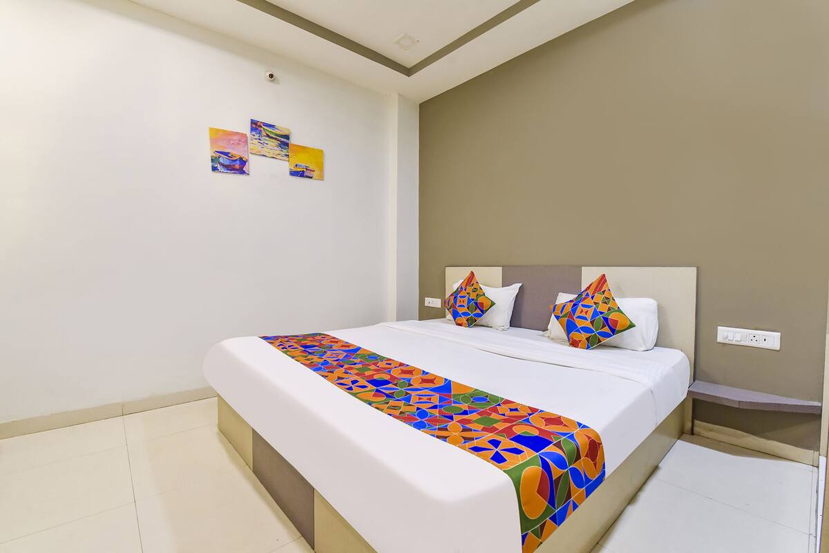 A neatly made bed with a colorful geometric-patterned bedspread, a white headboard, and two decorative pillows.