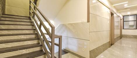 A modern interior with a staircase, marble walls, and a clean, well-lit hallway.