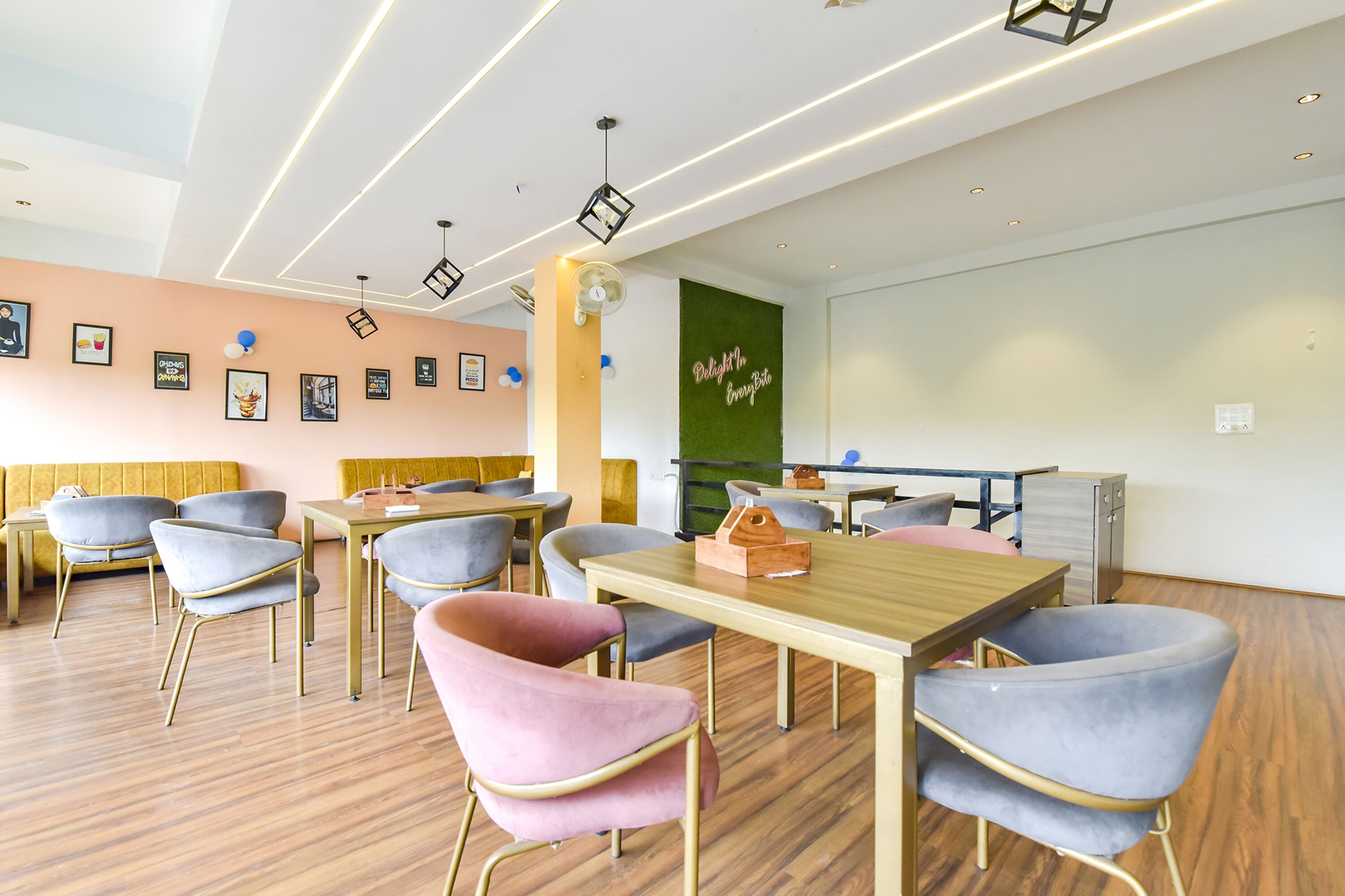 A modern conference room with wooden tables and chairs, a green accent wall, and ceiling lights.