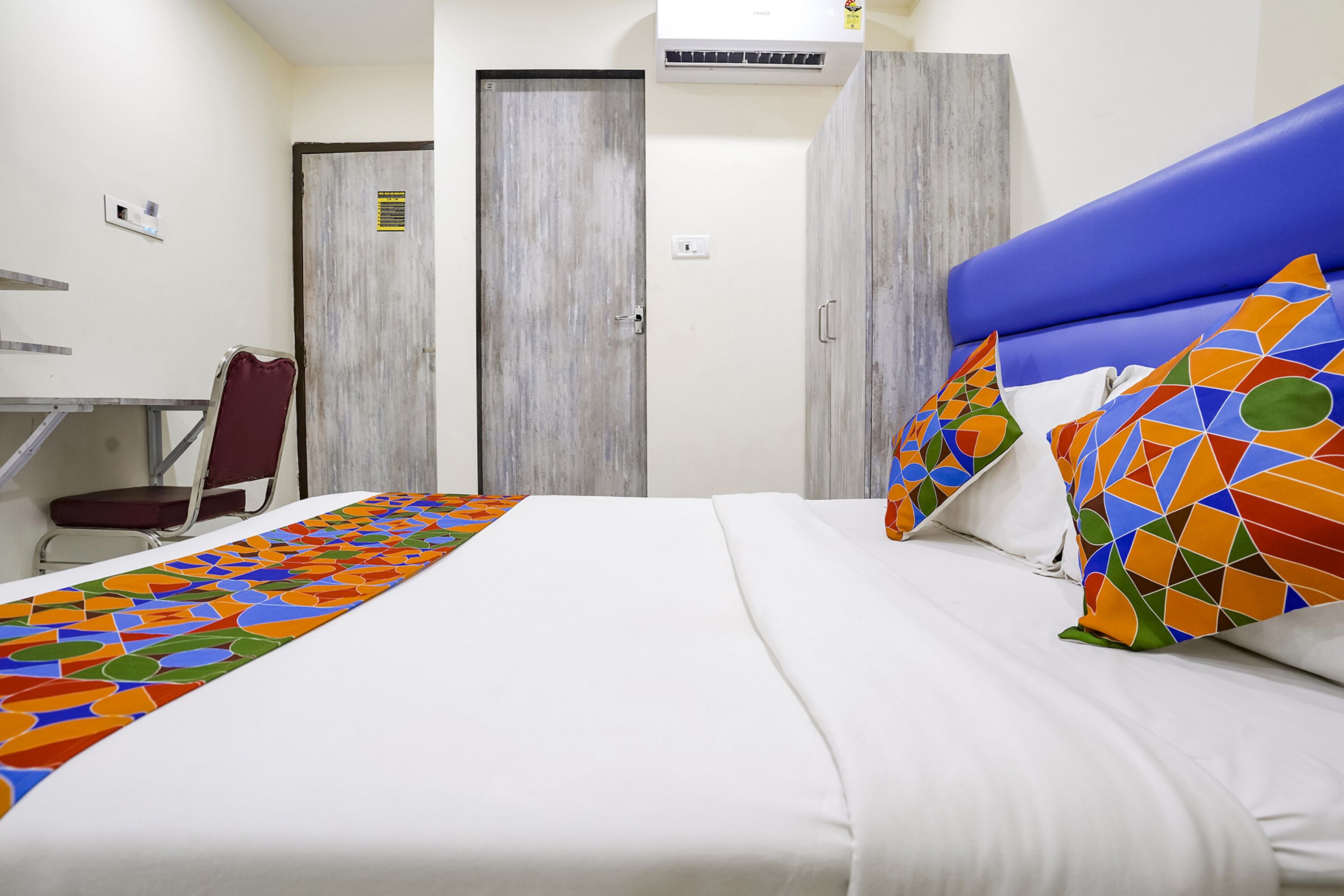 A hotel room with a bed, a desk, and a chair.