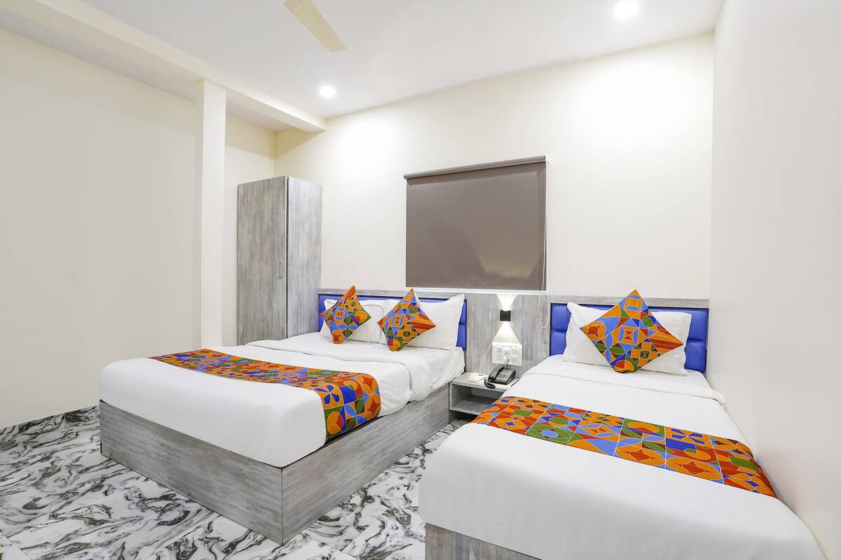 A hotel room with two beds, a marble floor, a large mirror, and a window with a blind.