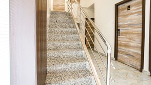 Un escalier avec une rampe en métal menant à une porte en bois portant le numéro 104.