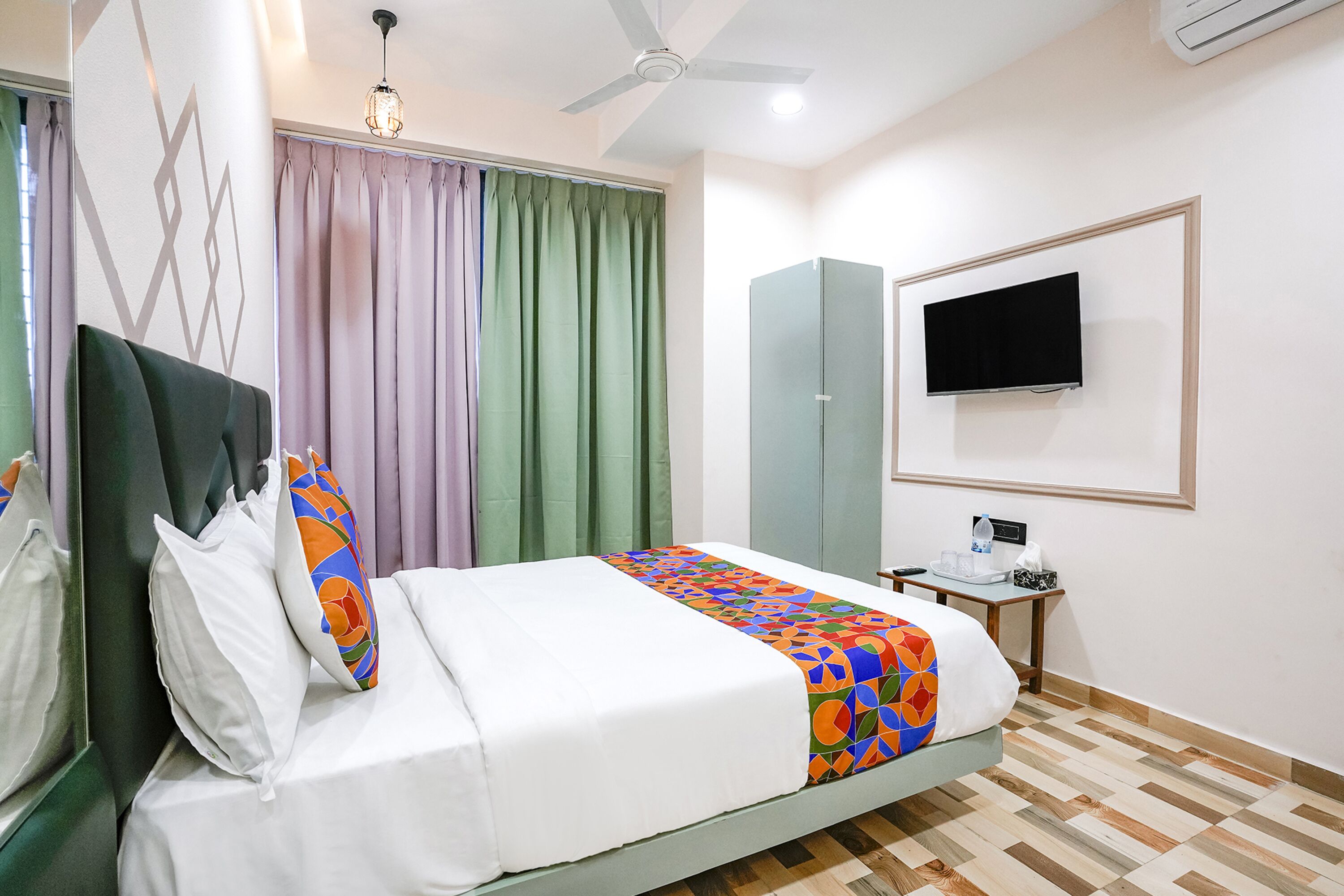 A hotel room with a bed, a desk, a television, and a wardrobe.