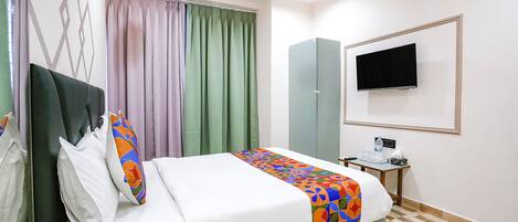 A hotel room with a bed, a desk, a television, and a wardrobe.