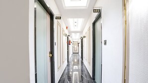 Un couloir d’hôtel avec un sol en marbre noir, des murs blancs et des portes numérotées 614 et 603.