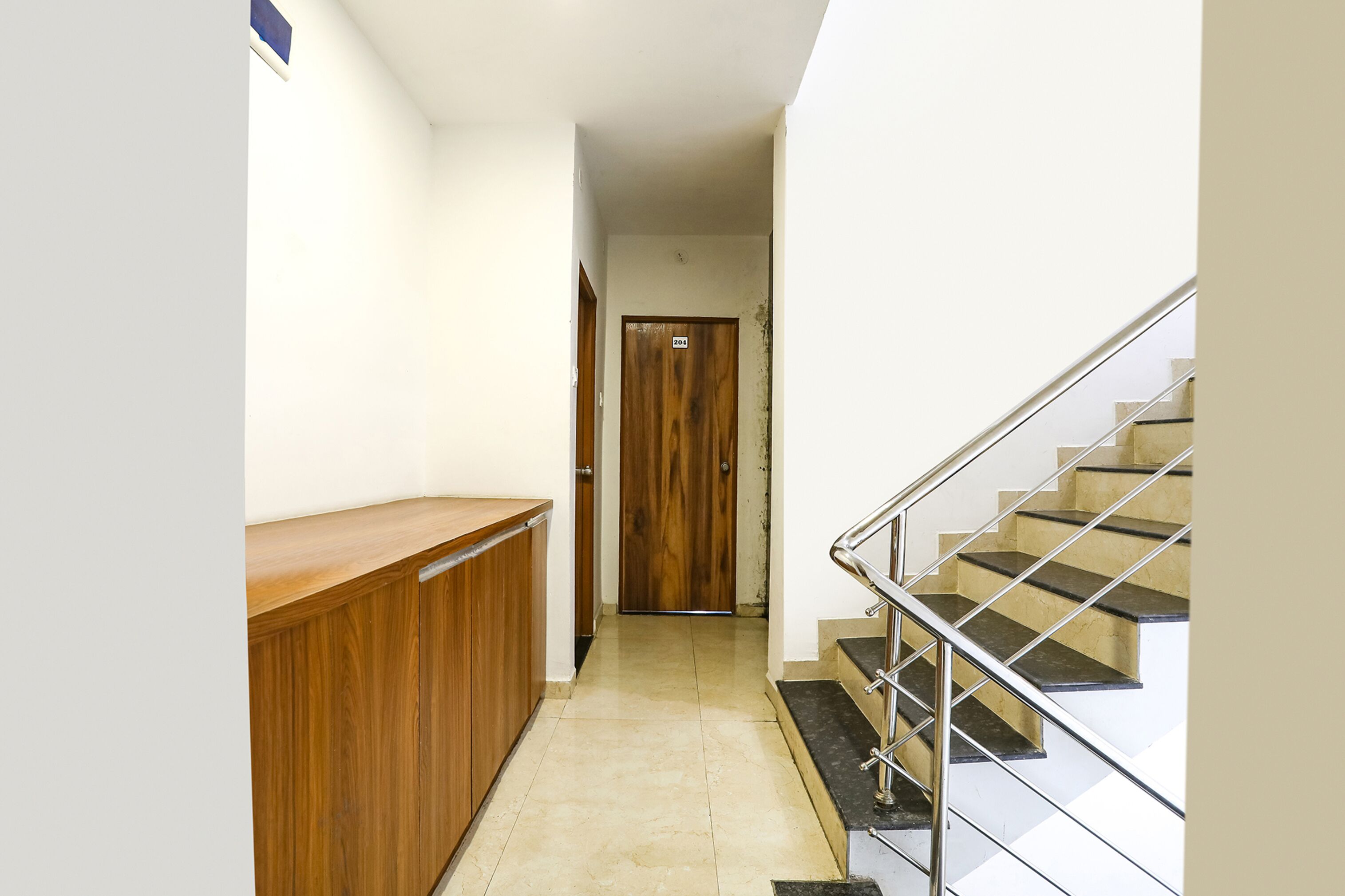 Ein Korridor mit einem Holzbüro, einer Holztür und einer Treppe mit Metallgeländern.