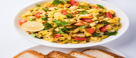 A bowl of scrambled eggs with vegetables and toast.
